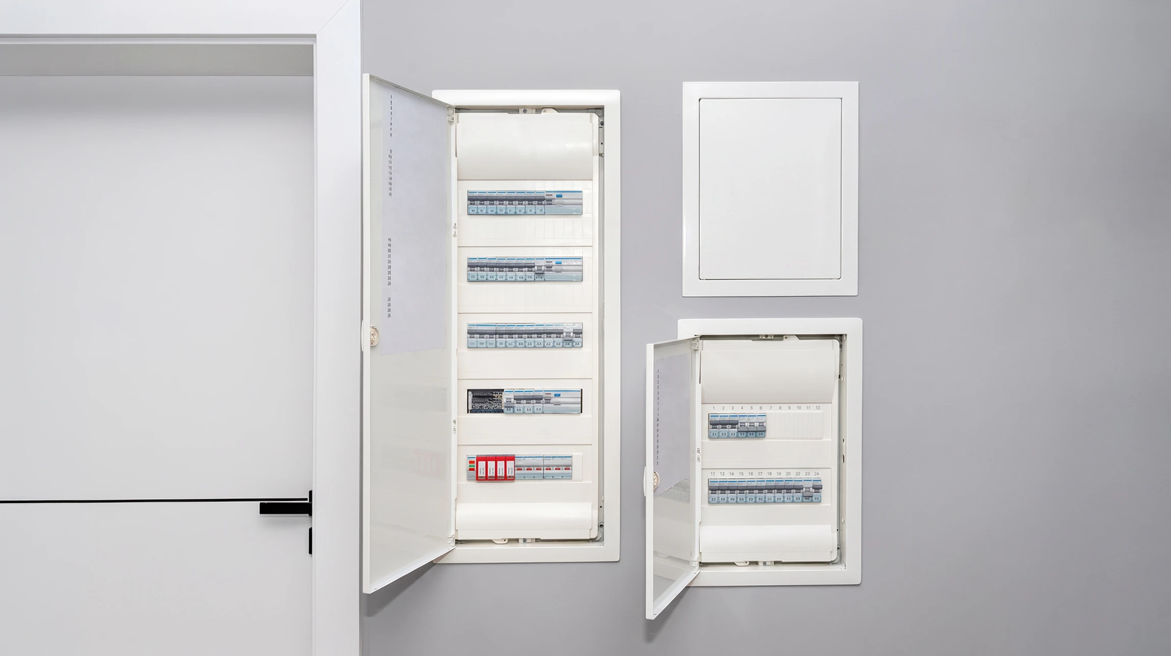 Électricien professionnel travaillant sur installation électrique résidentielle, manipulant multimètre et câblage dans boîtier mural